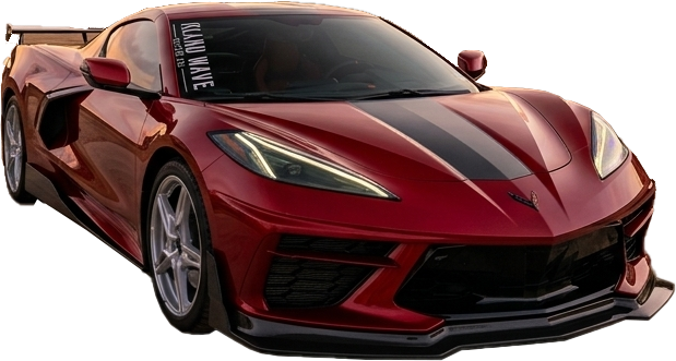 Red Chevrolet Corvette sports car with a black center stripe, viewed from the front-left on a dirt lot.