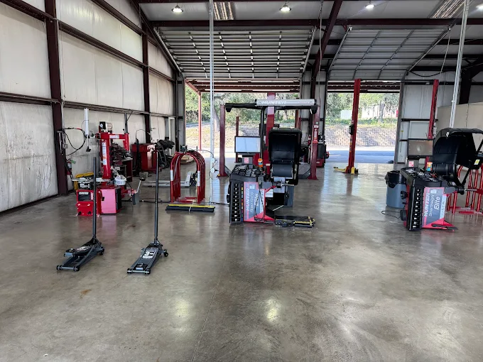 Industrial auto repair shop bay with two service lifts, drills, and tool stations arranged along the sides of the workshop.